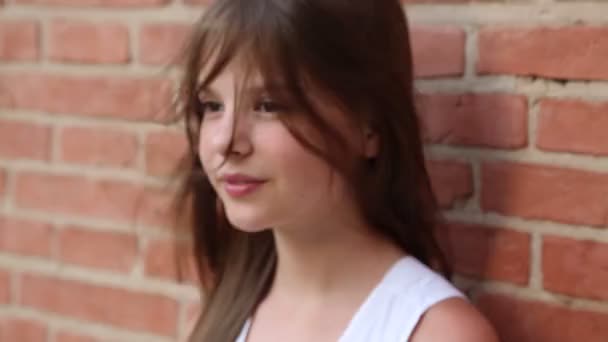 赤レンガの壁の上にモデルとしてポーズティーンの女の子 選択したフォーカス — ストック動画