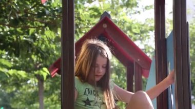 Genç kız dışarıda oyun bahçesinde oturuyor.