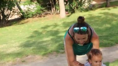 Anne küçük oğlunu kucağına alıp parkta dolaşıyor.