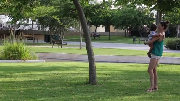 Mutter Hält Ihren Kleinen Sohn Und Posiert Vor Park Hintergrund — Stockvideo