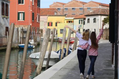 Genç kızlar Murano adasında turist olarak yürüyorlar, Veneto, İtalya