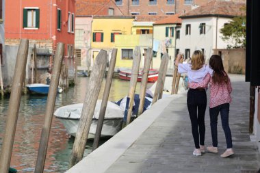 Genç kızlar Murano adasında turist olarak yürüyorlar, Veneto, İtalya