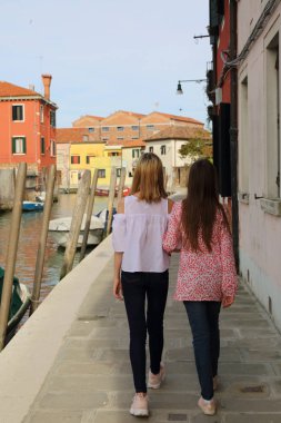 Genç kızlar Murano adasında turist olarak yürüyorlar, Veneto, İtalya