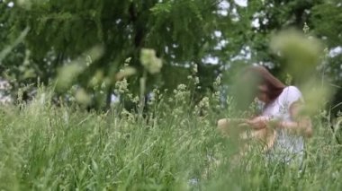 Kız hasır şapkasını küçük çayır çiçekleriyle süslüyor. Yazın dışarıda, yeşil çimlerin üzerinde. Seçili odak. Bulanık arkaplan. Bokeh.