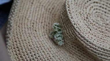 Kız hasır şapkasını küçük çayır çiçekleriyle süslüyor. Yazın dışarıda, yeşil çimlerin üzerinde. Seçili odak. Bulanık arkaplan. Bokeh.