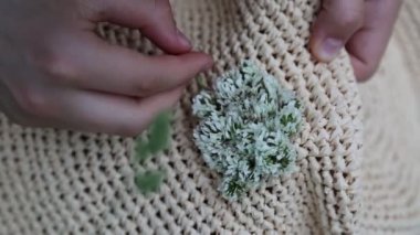 Kız hasır şapkasını küçük çayır çiçekleriyle süslüyor. Yazın dışarıda, yeşil çimlerin üzerinde. Seçili odak. Bulanık arkaplan. Bokeh.