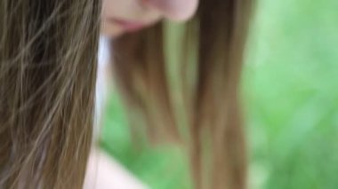 Kız hasır şapkasını küçük çayır çiçekleriyle süslüyor. Yazın dışarıda, yeşil çimlerin üzerinde. Seçili odak. Bulanık arkaplan. Bokeh.