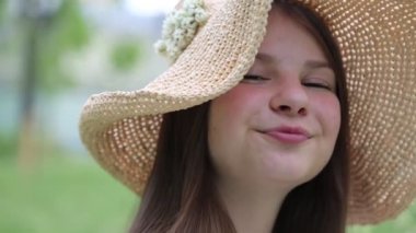 Yazın yeşil çimlerin üzerinde hasır şapkalı güzel beyaz kız. Seçili odak. Bulanık arkaplan. Bokeh.