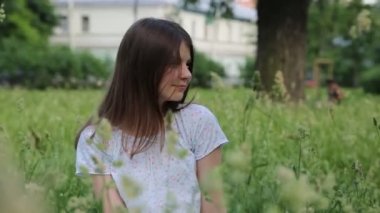 Yazın yeşil çimlerin üzerinde güzel beyaz bir kız. Seçili odak. Bulanık arkaplan. Bokeh.