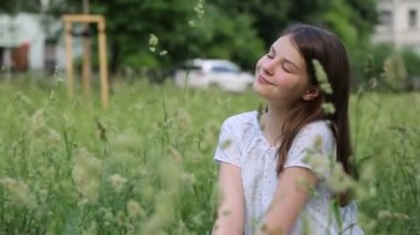 Yazın yeşil çimlerin üzerinde güzel beyaz bir kız. Seçili odak. Bulanık arkaplan. Bokeh.