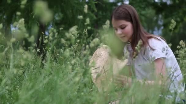 女の子は小さな牧草地の花で彼女のわらの帽子を飾る 夏に緑の草の中に外 選択したフォーカス 背景をぼかす ぼっけ — ストック動画