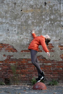 Kırmızı tuğlalı duvara karşı komik aktif genç gitl. Seçili odak.