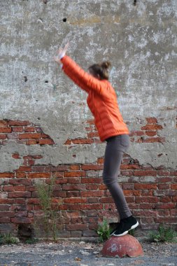 Kırmızı tuğlalı duvara karşı komik aktif genç gitl. Seçili odak.