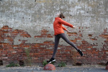 Kırmızı tuğlalı duvara karşı komik aktif genç gitl. Seçili odak.