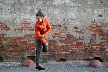 Kırmızı tuğlalı duvara karşı komik aktif genç gitl. Seçili odak.