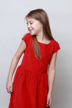 Duygusal çocuk kamerada poz veriyor ve dans ediyor. Kırmızı elbiseli küçük kız..