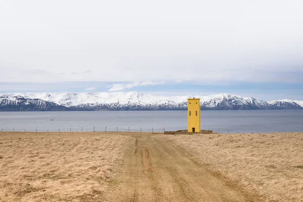 Sarı bir deniz feneri fjords İzlanda'daki bir uçurumun üzerinde duruyor