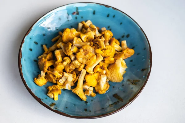 Taze yıkanmış ve beyaz masa üzerinde mavi bir kasede Cantharellus cibarius temizledim