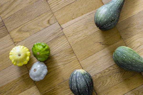 İle küçük tarak squashes hafif kahverengi ahşap zemin üzerinde üç yeşil kabak