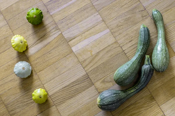 İle küçük tarak squashes hafif kahverengi ahşap zemin üzerinde üç yeşil kabak