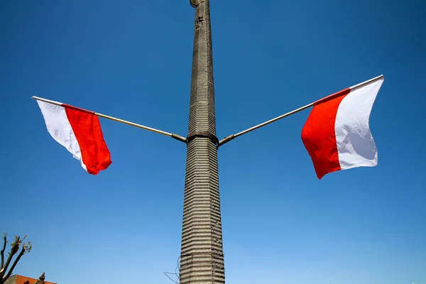 Two Polish flags waving on a lamppost