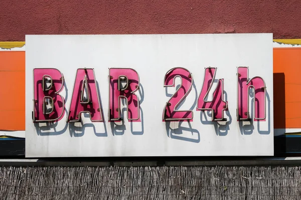 24h open bar - old neon sign in daylight