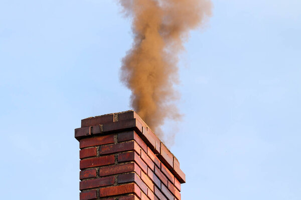 Thick smoke billowing out of a house chimney causing air pollution / smog 