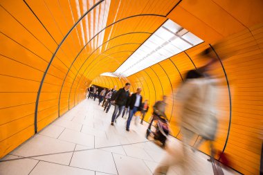 Metro koridorunda koşuşturan insanlar (hareket bulanıklığı tekniği hareketi iletmek için kullanılır))
