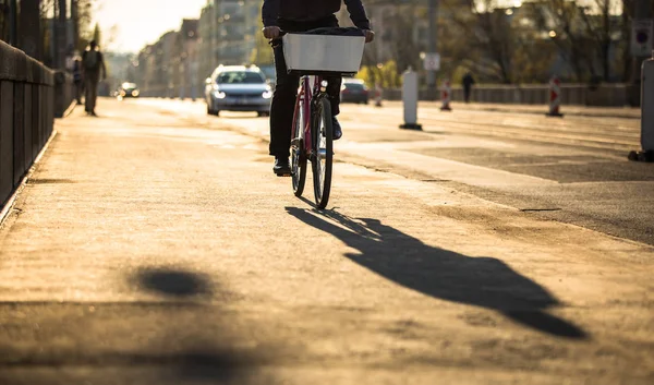 在温暖的黄昏阳光下的城市街道上骑车的车手 — 图库照片