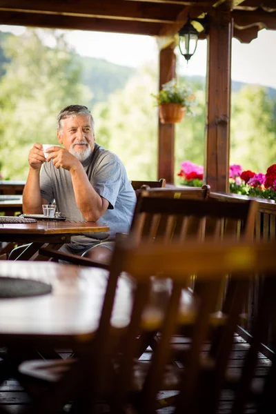 山のホテルのテラス 休暇中に彼の朝のコーヒーを楽しんでいるハンサムな年配の男性 — ストック写真