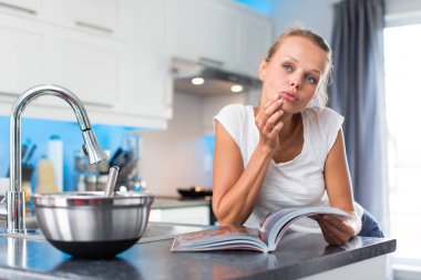Güzel, genç kadın onun modern, temiz ve parlak mutfağında, öğle yemeği düzenleme (renk tonlu imaji; sığ DOF)