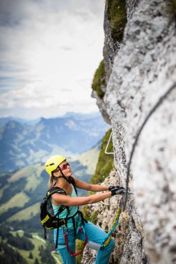 Ferrata üzerinden İsviçre Alplerinde kayaya tırmanan güzel bir bayan tırmanıcı.