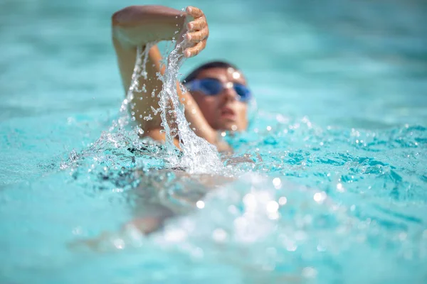 男子游泳者在蓝色的游泳池里爬泳 一名身穿泳镜的年轻男子游泳爬行运动员的肖像 铁人三项全能运动员训练 — 图库照片
