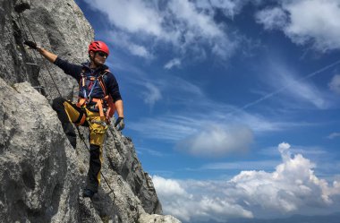 Young man climbing on a rock in Swiss Alps - via ferrata/klettersteig clipart