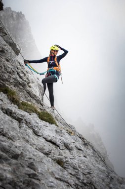 Ferrata üzerinden İsviçre Alplerinde kayaya tırmanan güzel bir bayan tırmanıcı.