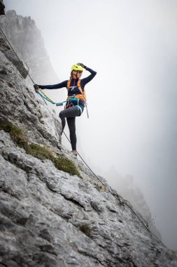 Pretty, female climber on a via ferrata - climbing on a rock in Swiss Alps clipart