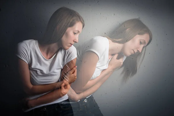 Young woman suffering from a severe depression/anxiety (color toned image; double exposure technique is used to convey the mood of unease, progression of the anxiety/depression)