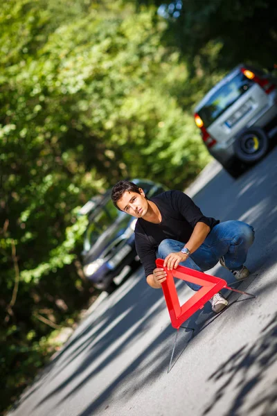 一个英俊的年轻人 他的车在路边抛锚 设置了一个安全的三角形 — 图库照片