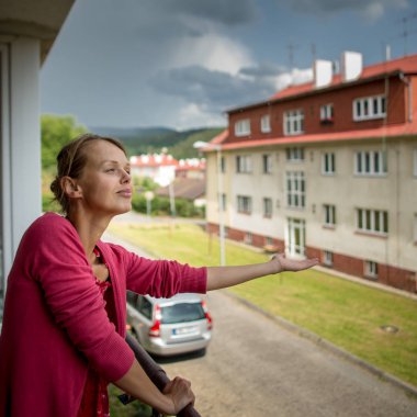 Güzel, genç kadın hava kontrol onun daire balkonundan yağıyor