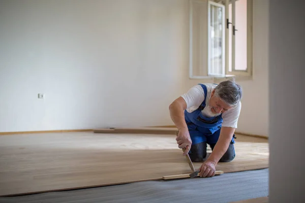 Diy 建物や家庭のコンセプト 寄木細工の床板 積層床に横たわっている男性の手のクローズアップ 浅いDof カラートーン画像 — ストック写真