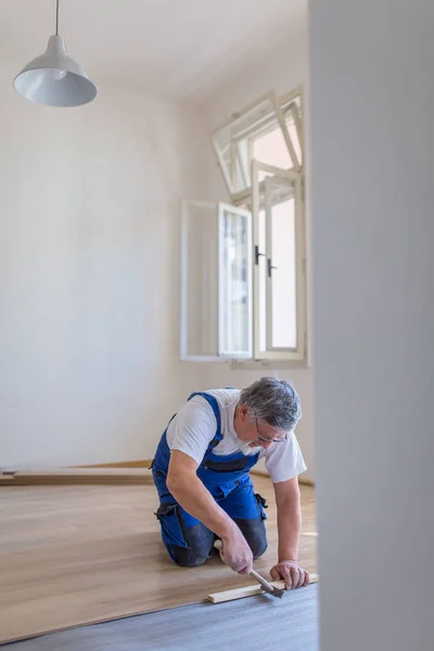 Diy 建物や家庭のコンセプト 寄木細工の床板 積層床に横たわっている男性の手のクローズアップ 浅いDof カラートーン画像 — ストック写真