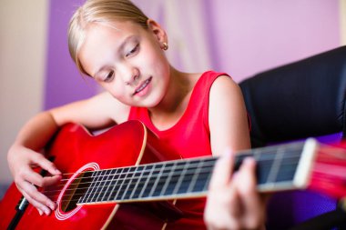 Güzel odasında gitarı olan genç bir kız.