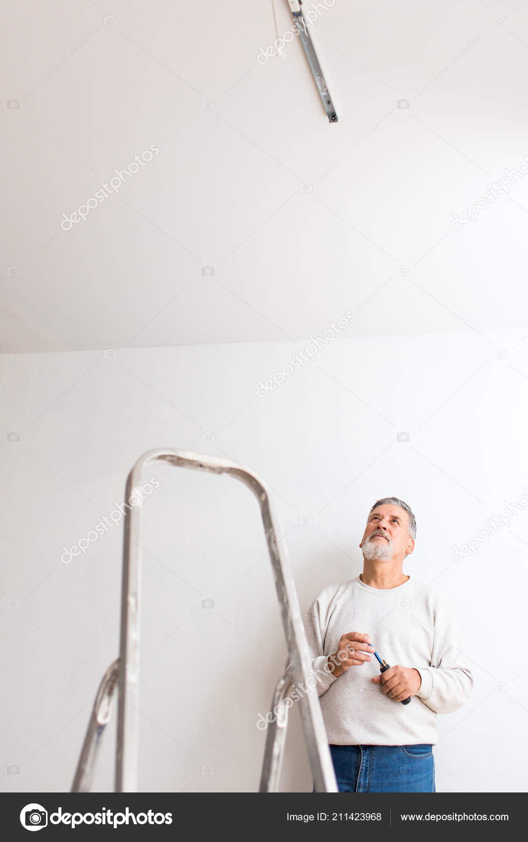 Senior Man Installing Ceiling Light Freshly Renovated Appartment