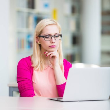 Kütüphanedeki güzel genç üniversite öğrencisi (sığ DOF; renk tonlu resim)