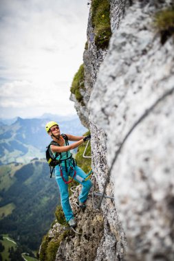 Ferrata üzerinden İsviçre Alplerinde kayaya tırmanan güzel bir bayan tırmanıcı.