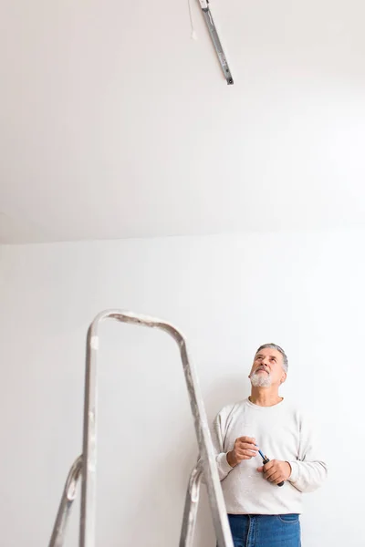 高级男子安装天花板灯 一个新装修的公寓 — 图库照片