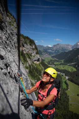 Ferrata üzerinden İsviçre Alplerinde kayaya tırmanan güzel bir bayan tırmanıcı.