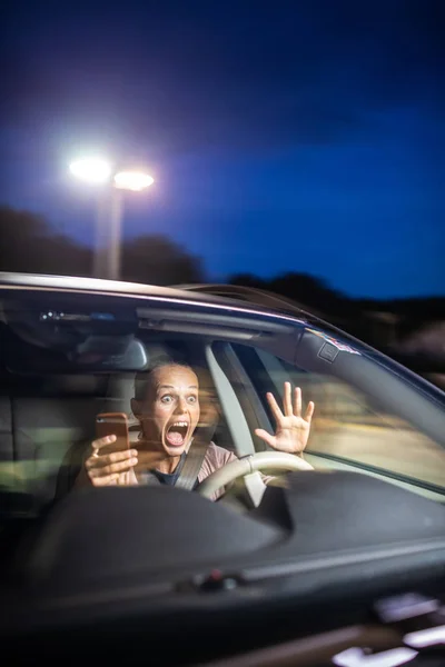 潜在的に危険な状況で驚いた運転に注意を払うのではなく 彼女の携帯電話で遊ぶ若い女性ドライバー 道路安全コンセプト — ストック写真