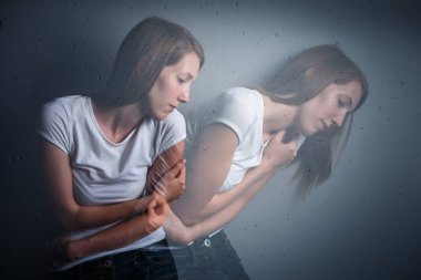 Young woman suffering from a severe depression/anxiety (color toned image; double exposure technique is used to convey the mood of unease, progression of the anxiety/depression) clipart