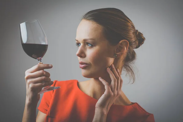赤ワインのグラスを持って 赤いドレスでエレガントな若い女性 — ストック写真